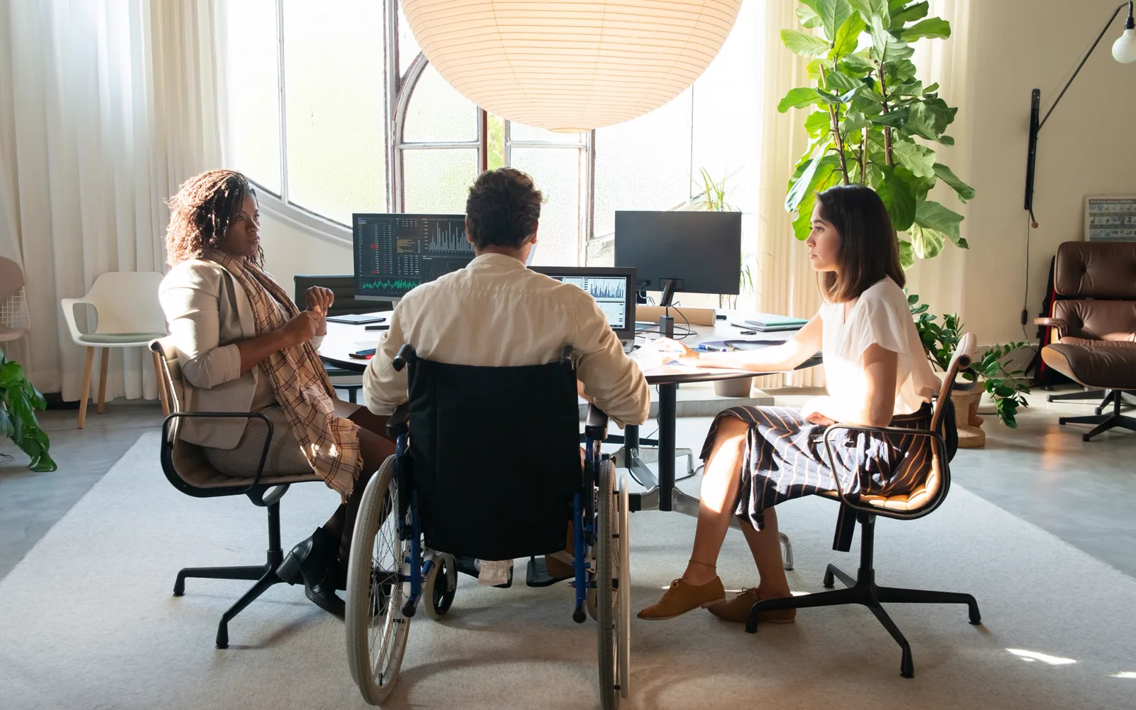 Trois professionnels échangent autour d’une table de travail.